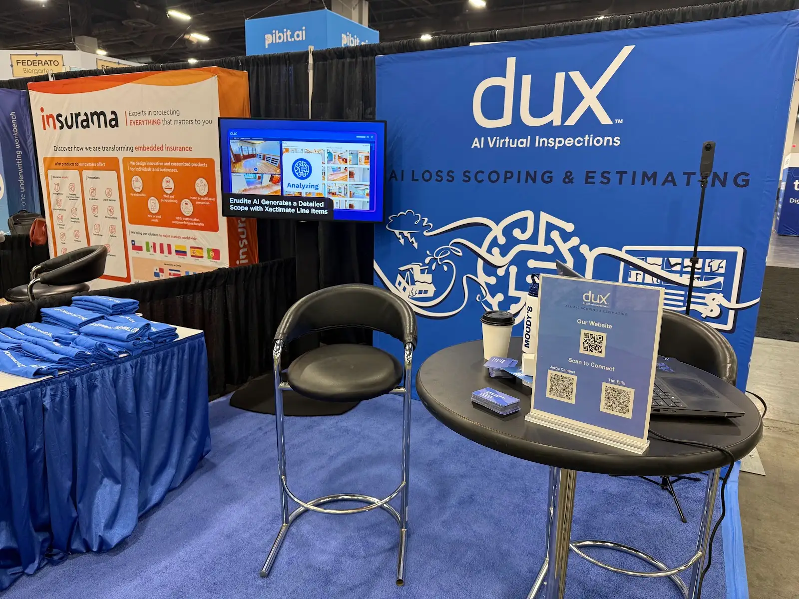 The empty DUX booth at ITC, with a blue branded backdrop and Erudite product screen.